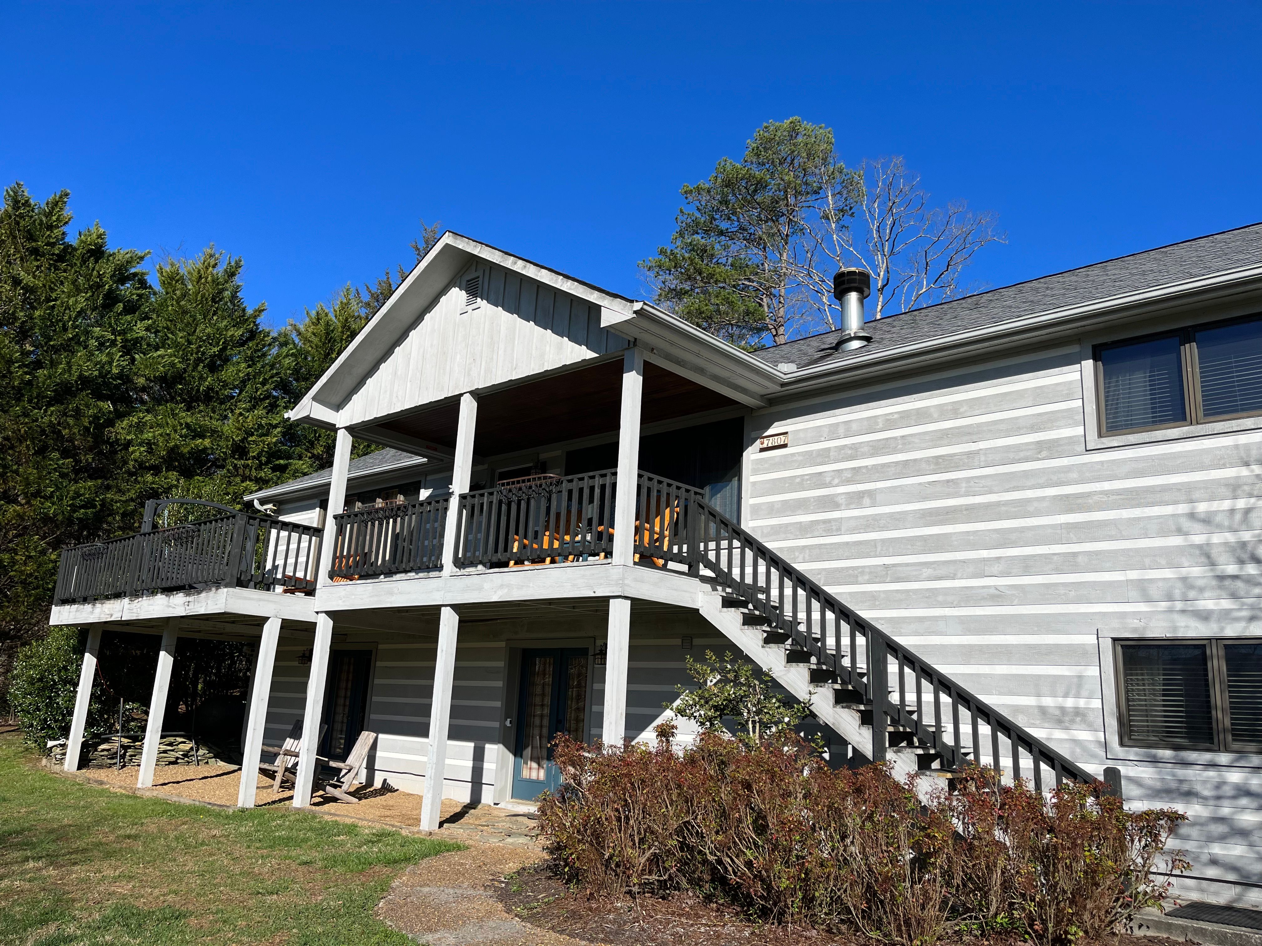Cedar Creek Manor, freshly painted, on the crest of its hill wrapped by a covered porch