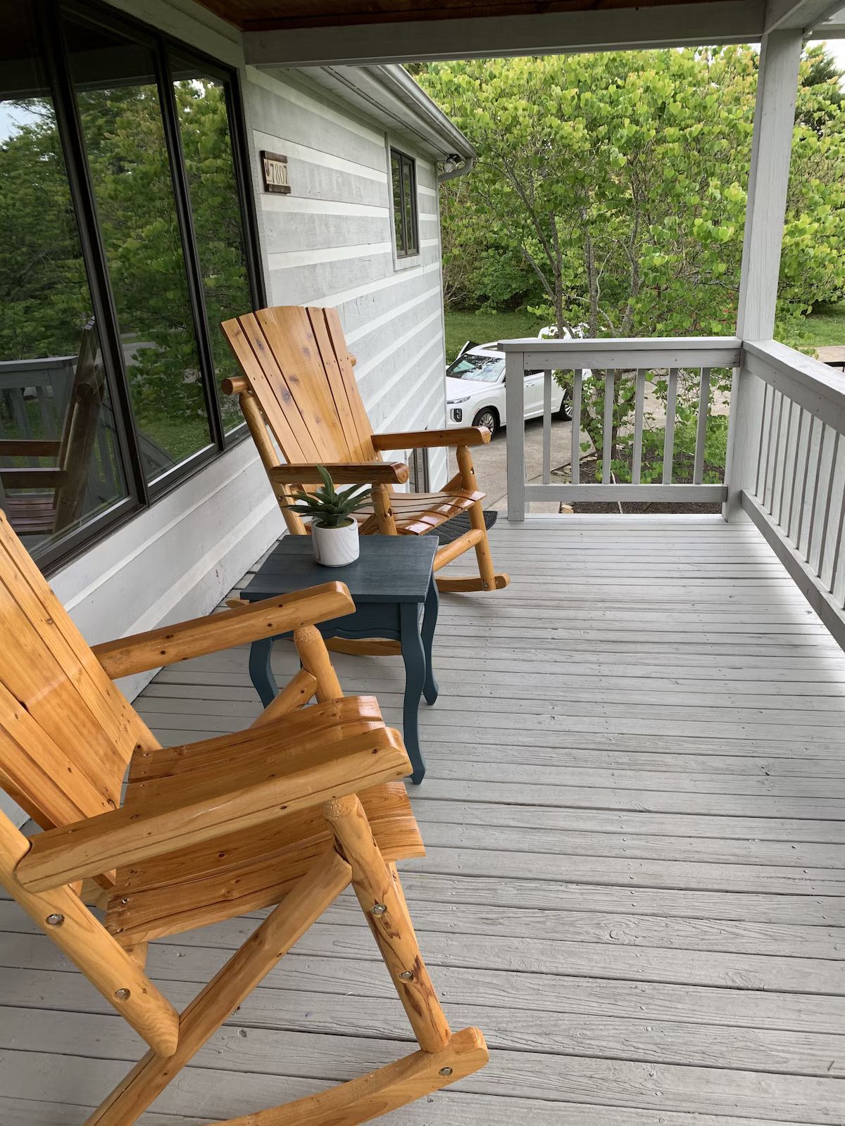 A row of rocking chairs lined up along the covered front porch facing the mountains