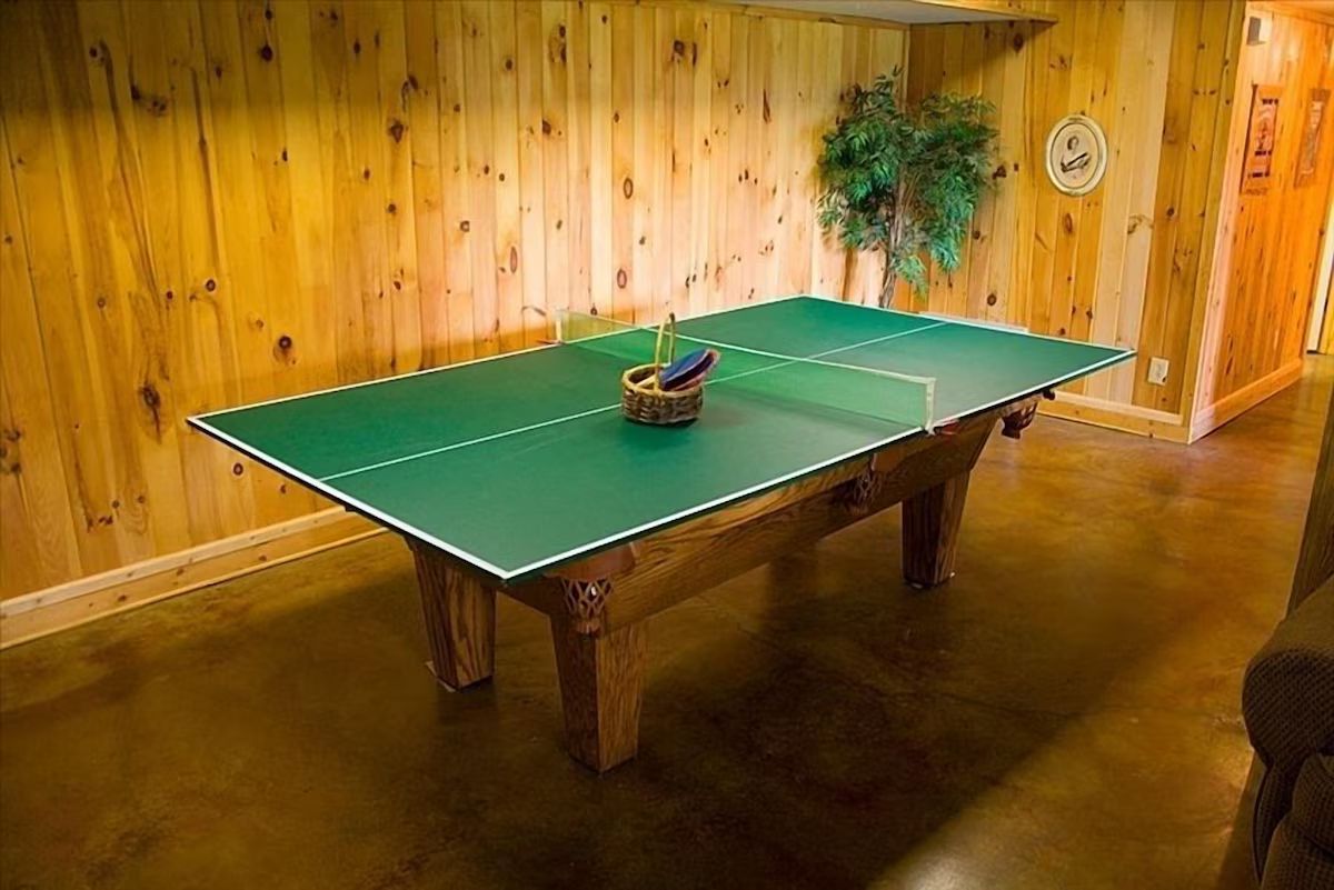 The lower-level game room with a pool table topped for ping-pong, ready for a tournament