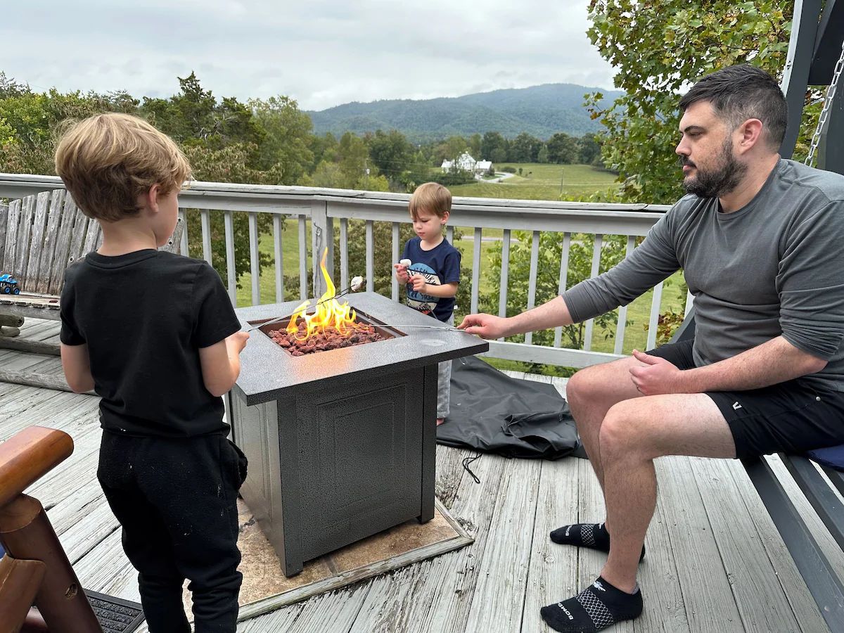 Family roasting marshmallows over the gas fire pit on the front deck